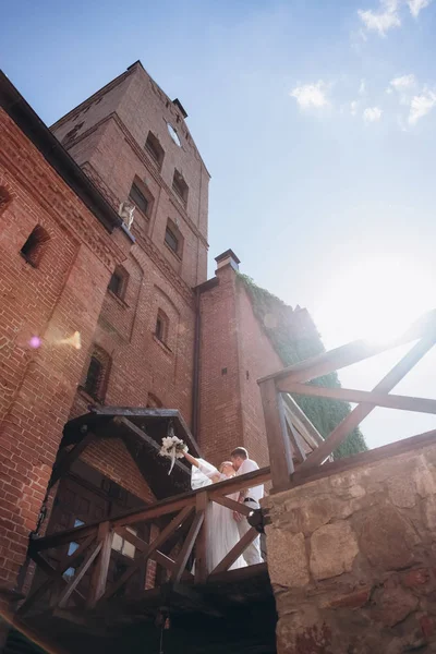 Blick von unten auf Braut und Bräutigam, die sich vor dem Eingang zum antiken Schloss küssen — Stockfoto