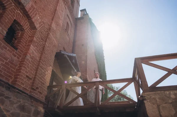 Vista inferior de la novia y el novio en frente de la entrada al antiguo castillo - foto de stock