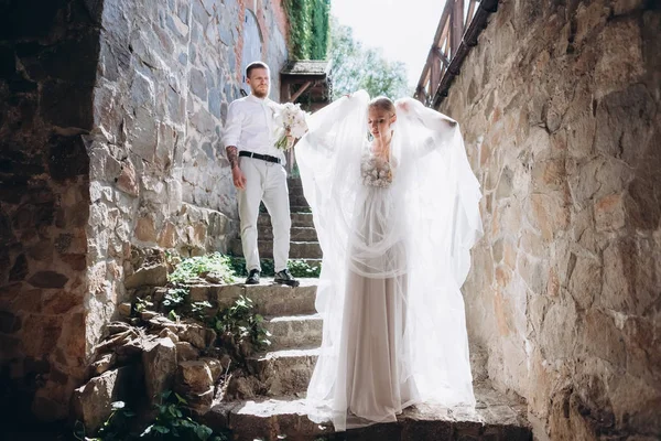 Schöne Braut und schöner Bräutigam auf der Treppe eines alten Gebäudes in der Altstadt — Stockfoto