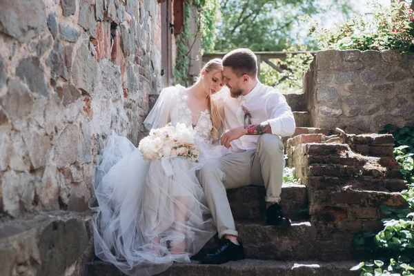 Bride and groom sitting on stairs at old town — Stock Photo