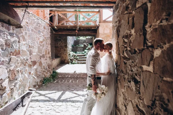 Beautiful young cuddling bride and groom inside of ancient building — Stock Photo