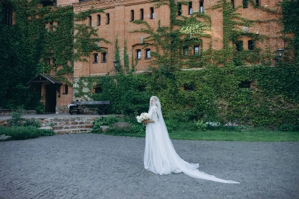 Attractive young bride in garden in front of ancient building — Stock Photo