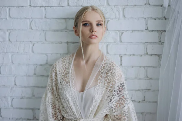 Atractiva mujer joven en estilo negligee en frente de la pared de ladrillo blanco - foto de stock