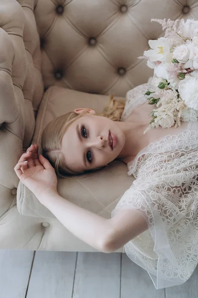 High angle view of beautiful young woman with white bouquet lying on couch — Stock Photo