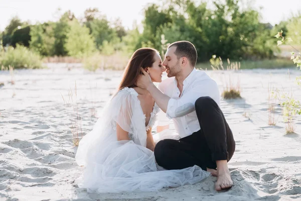 Feliz pareja besándose y sentado en hermosa playa - foto de stock