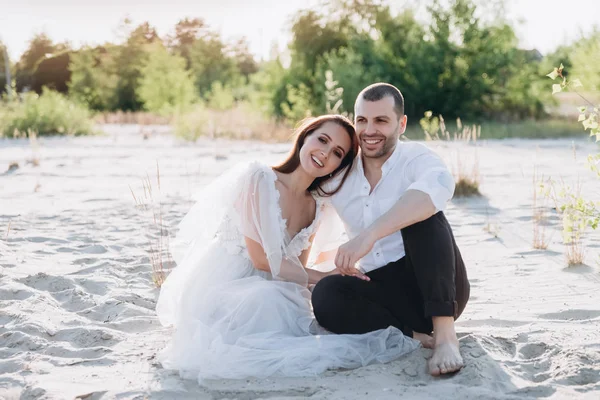 Красивая счастливая пара улыбается и сидит на пляже — стоковое фото