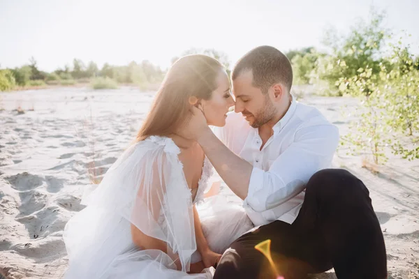 Schönes glückliches Paar sitzt am Strand — Stockfoto