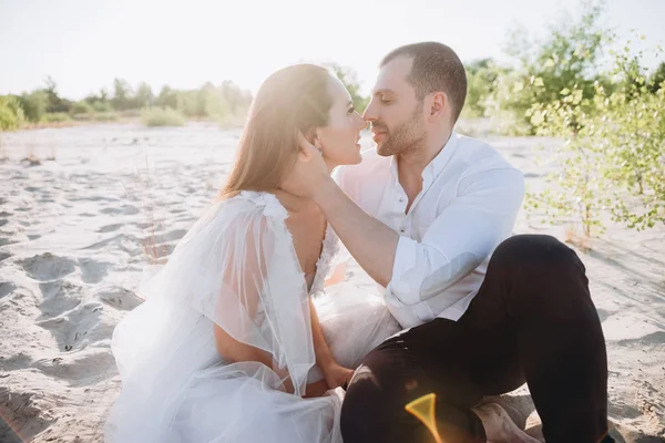 Feliz tierna pareja va a besar mientras está sentado en la playa - foto de stock