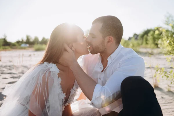 Hermosa feliz pareja besándose en la playa con luz de fondo - foto de stock