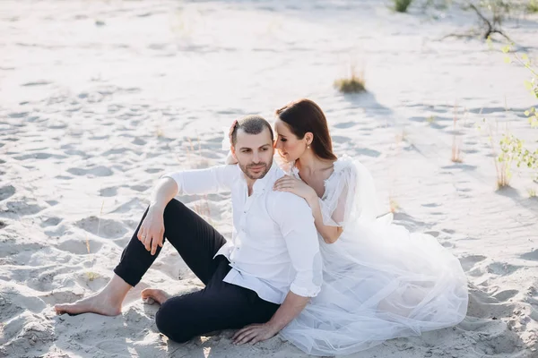 Hermosa familia joven abrazando y sentado en la playa - foto de stock