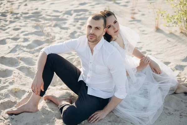 Hermosa pareja feliz sentado en la playa de arena - foto de stock