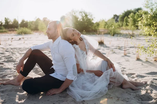 Hermosa feliz tierna pareja sentado en la playa - foto de stock