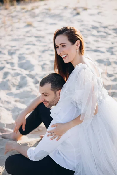 Bella coppia sorridente seduta sulla spiaggia di sabbia — Foto stock