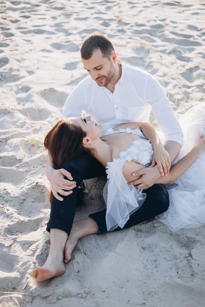 Attractive girl lying on boyfriend laps on sandy beach — Stock Photo