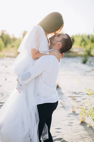 Bell'uomo che tiene la sua ragazza sulle mani sulla spiaggia — Foto stock