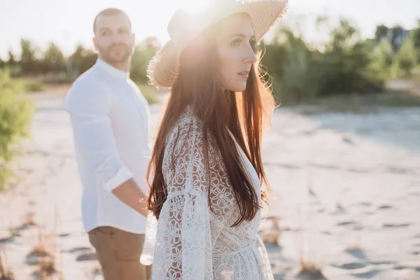 Bela mulher de chapéu de mãos dadas com o homem na praia — Fotografia de Stock