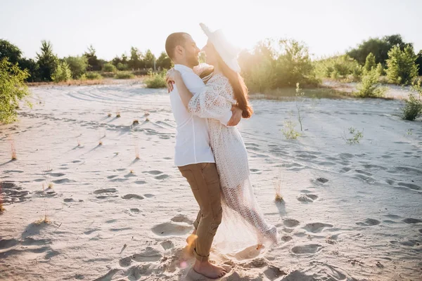 Beautiful young couple hugging on sandy beach with back light — Stock Photo