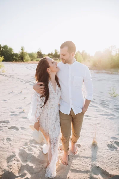Щаслива стильна пара обіймається на пляжі з заднім світлом — стокове фото