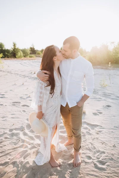 Feliz pareja abrazos y besos en la playa con retroiluminación - foto de stock