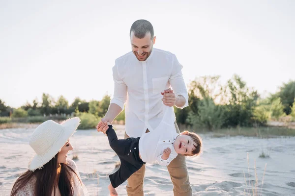 Beautiful happy parents playing with little baby on beach — Stock Photo