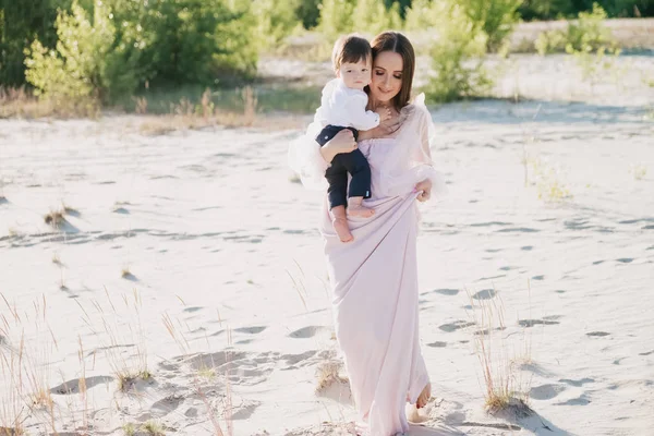 Young mother holding little baby on hands while walking on beach — Stock Photo