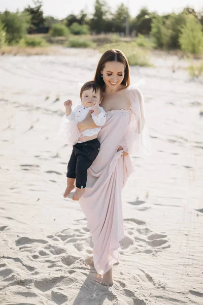 Attractive mother holding little son on beach — Stock Photo