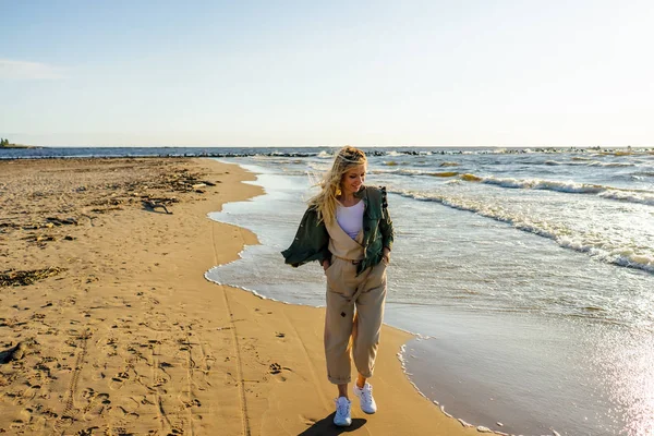 Молода усміхнена жінка в стильному одязі на березі моря в літній день — стокове фото