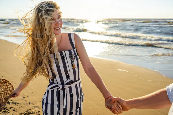 Visão parcial de mulher sorridente segurando a mão namorados enquanto caminhava na praia de areia — Fotografia de Stock