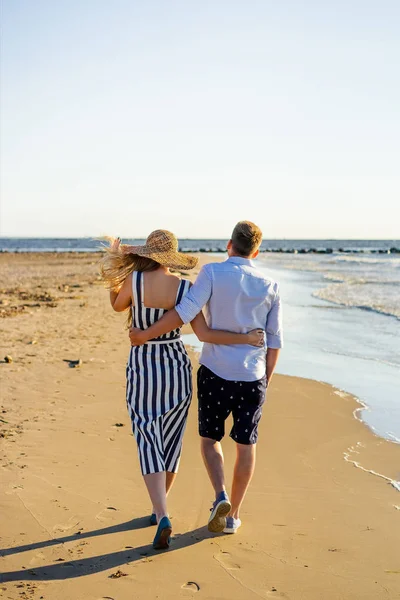Rear view of affectionate couple walking on sandy beach on summer day — Stock Photo