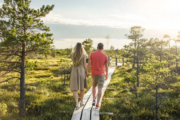 Back view of couple in love walking on wooden bridge with blue sky on background — Stock Photo