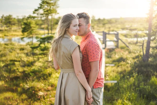 Ritratto di tenera coppia innamorata su ponte di legno con piante verdi sullo sfondo — Foto stock