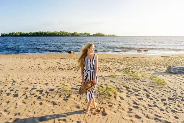 Belle femme souriante avec chapeau de paille debout sur la plage de sable seul avec mer sur fond — Photo de stock