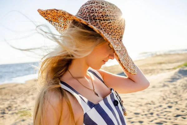 Vista lateral de la atractiva joven en sombrero de paja en la playa de arena en Riga, Letonia - foto de stock
