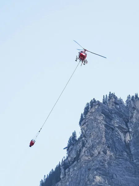 Fire helicopter with water tank in the air near kandersteg switzerland