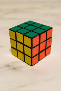 Yeşil, sarı ve turuncu closeup gösterilen Rubik küpü bir mermer plaka üzerinde