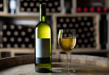 beyaz şarap şişesi bir kiler, İsviçre bir varil üzerinde dolu bardaklı