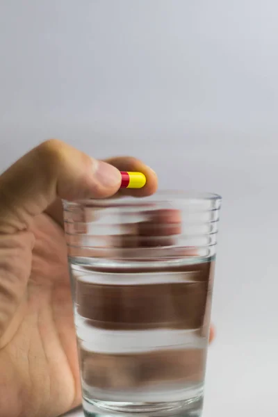 Mannen Geeft Een Rood Geel Gekleurde Pil Een Glas Water — Stockfoto