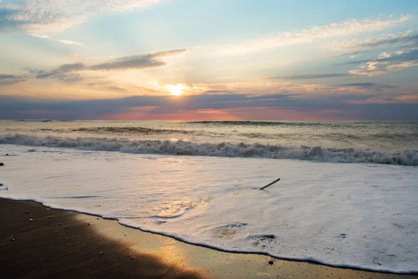 Günbatımı kumlu plaj, köpüklü dalga