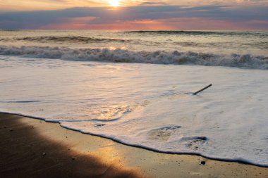 Günbatımı kumlu plaj, köpüklü dalga