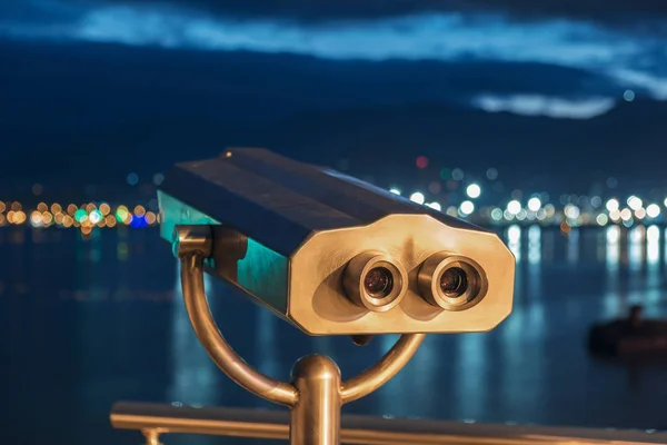 View of the blurred night seaside city from the binocular