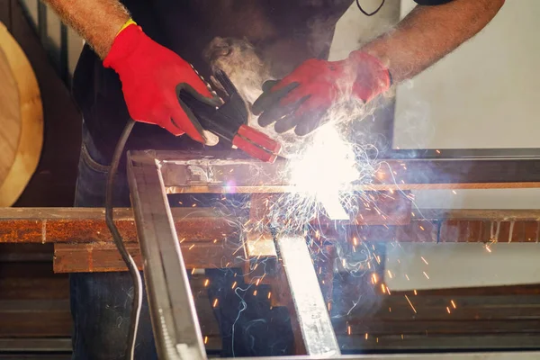 Worker welding metal construction in the workshop