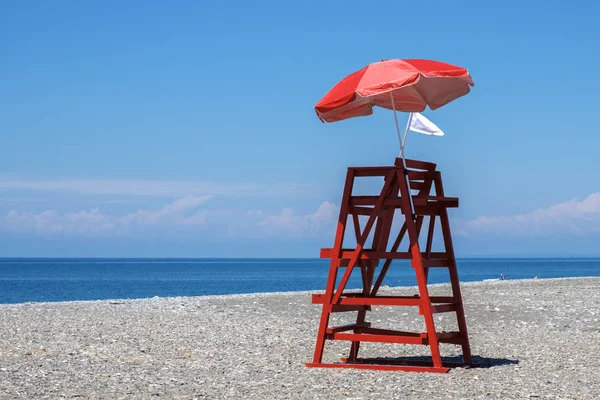 Red rescue tower and beach umbrella — Stock Photo, Image