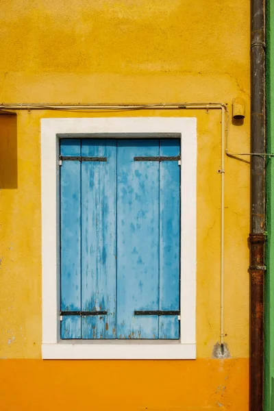 Janela velha com cortinas fechadas de madeira azuis no amarelo gasto w — Fotografia de Stock