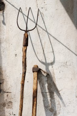 Grunge duvarda paslı iyi kullanılan bahçe çatalı ve çapa