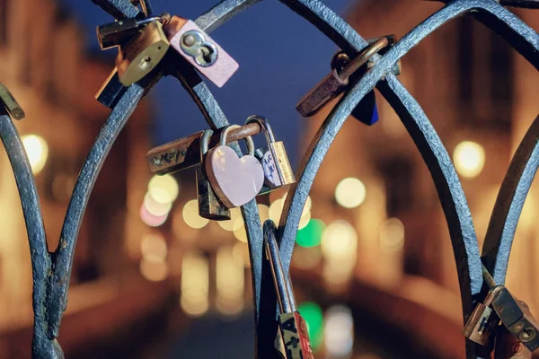 Row of color love locks on the bridge across the canal at night — Stock Photo, Image