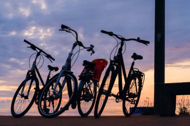 Gün batımı bulutlu gökyüzü geri sahilde bisiklet silueti