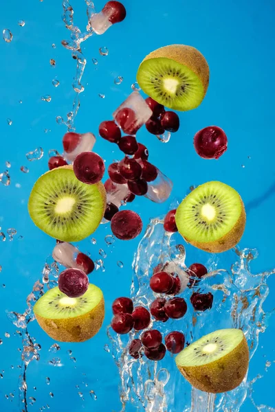 Falling fresh mixed fruits. Slices of the kiwi and cherry with fresh water in the air. Flying fruits concept.
