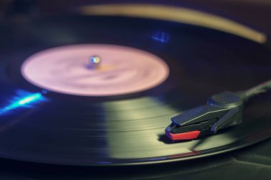 Dönen siyah vinil plaklı, yeşil ve mavi ışıkları yansıtan Retro kayıt çalar
