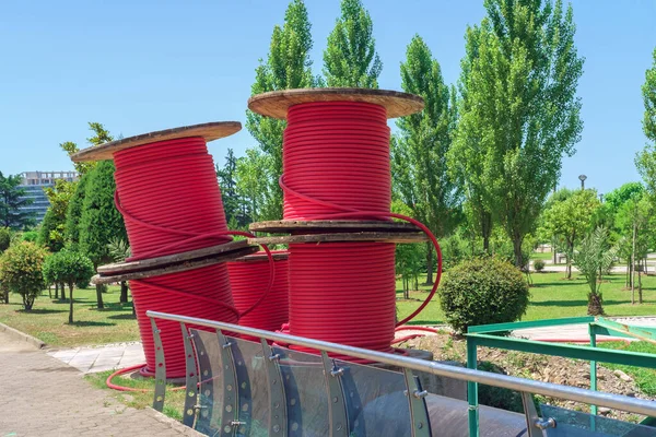 Wooden coils with red power cables in the park