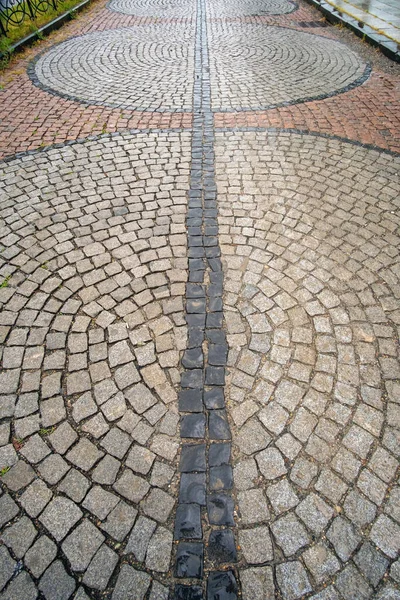 Traditional wet stone pavement in perspective after the rain. Abstract background of old cobblestone pavement